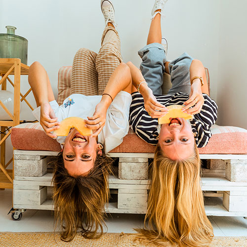 Los momentos compartidos saben mejor con melón Waikiki. Foto divertida de dos amigas divirtiéndose y disfrutándolo.